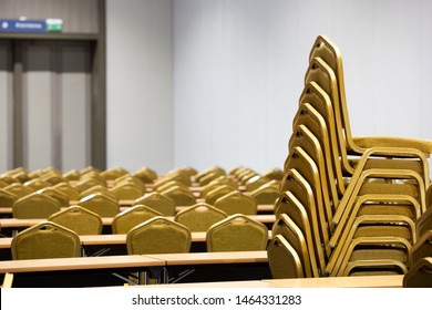 Stack Steel Chair Fabric Seat Pad Yellow Gold Color And Table Arrange In Row Ready To Set Up For Big Meeting, Conference, Business, Workshop, Gala Dinner, Wedding Ceremony In Convention Hall Of Hotel