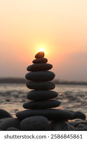 A stack of stones on the beach at sunset.