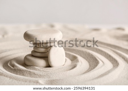 Stack of stones on light sand with lines against grey background. Zen concept