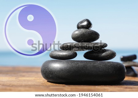 Stack of stones on wooden table outdoors and Ying Yang symbol. Feng Shui philosophy 