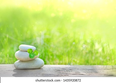 Stack of stones and Shamrock clover leaf on table, green natural background. composition with zen pebble stones. symbol of spa, soul and body Relax. tranquil, peaceful, calmness, life balance concept