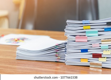Stack of student's homework that assigned to students to be completed outside class on teacher's desk separated by colored paper clips. Document stacks arranged by various colored paper clips on desk. - Shutterstock ID 1077661538