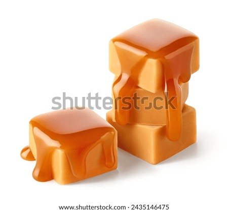 Stack of sweet caramel candy cubes topped with caramel sauce isolated on white background