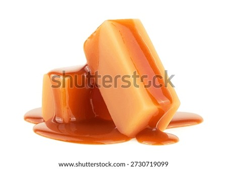 Stack of sweet caramel candy cubes topped with caramel sauce isolated on a white background. Two pieces of caramel.