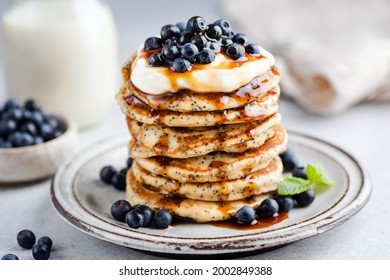 Stack of tasty Poppy seed Pancakes with maple syrup, yogurt and blueberries. Sweet breakfast food
