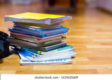 Stack of Textbooks and Black Backpack on Wooden Floor. Education, School Holidays, Back to School Concept. Copy Space.