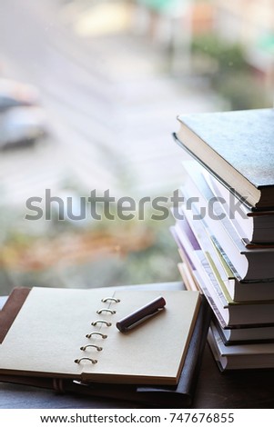 A stack of textbooks on the windowsill and writing utensils