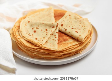 Stack of thin pancakes on white table. Crepes, blini. Front view