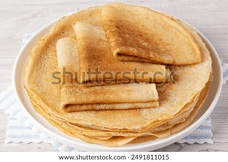 A stack of thin pancakes on a white table