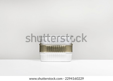 A stack of three canned food tins on a white surface