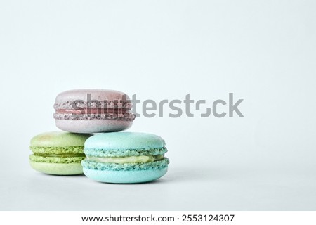 Stack of three colorful French Macarons, cakes with different flavors stacked in a pyramid, mint, apple, currant flavor. homemade dessert, macaroons aquamarine, green, purple color on gray background