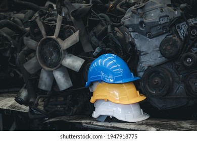 Stack of three colorful worker helmets at workplace manufacturing plant factory construction site building with many engine parts as background.