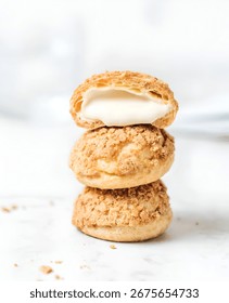 A stack of three cream puffs, with the top one cut open to reveal the creamy filling.