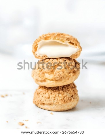 A stack of three cream puffs, with the top one cut open to reveal the creamy filling.