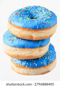Stack of three delicious blue glazed donuts with colorful sprinkles isolated on a white background