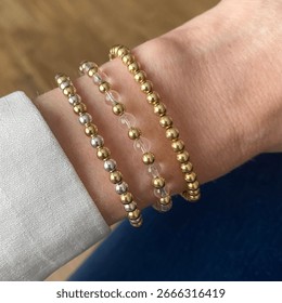 A Stack Of Three Gold And Silver Beaded Bracelets On Wrist
