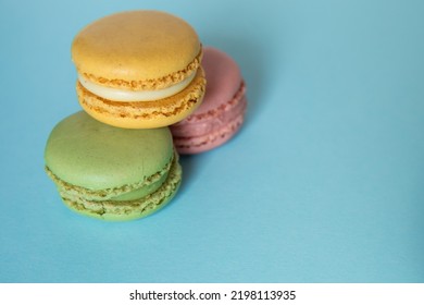 Stack Of Three Green, Pink And Blue Macarons On Blue Background. Concept Of Sweet Temptation, Caprice. Copy Space