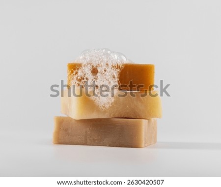 Stack of three handmade natural soap bars with foam and bubbles on a white background. Clean and minimalistic composition. Ideal for eco, skincare, and wellness concepts.