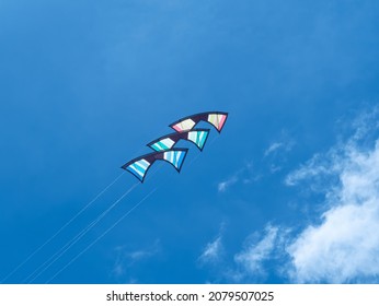 Stapel von drei Quad-Linie Stunt-Drachen gegen einen blauen Himmel.