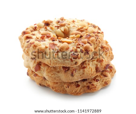 Stack of three round peanut cookies with chopped nuts and whole peanuts, delicious sweet snack food isolated on white background
