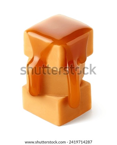 Stack of three sweet caramel candy cubes topped with caramel sauce isolated on white background
