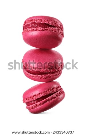 A stack of three vivid red macarons levitated in mid-air isolated on a white background. Sweet French sandwich cookies.