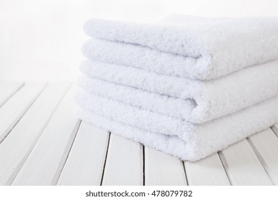 Stack Of Three White Fluffy Bath Towels On The Background Of White Boards