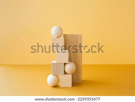 Stack of three-dimensional wooden figures on yellow background. Balance concept.