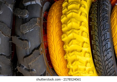 stack of tires for for agriculture machines,for sale.yellow,orange and black colors tires.outside market,shop,synthetic rubber.fat bike tire.wheelbarrow solid wheel.gardening,farming concept - Shutterstock ID 2178524061