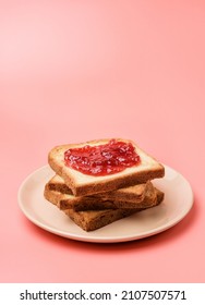 A stack of toasts with jam on a dish close-up. Plate with pieces of toasted bread on a pink background with copy space. - Shutterstock ID 2107507571