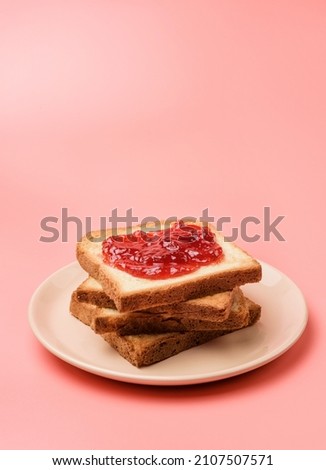 A stack of toasts with jam on a dish close-up. Plate with pieces of toasted bread on a pink background with copy space.