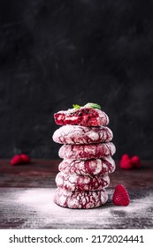 Stack or tower of cookies. Red velvet cookies. Chefs hands with small sieve for baking sprinkling powdered sugar. Baker decorating and sprinkling stack of cookies. Dark background, colourful food