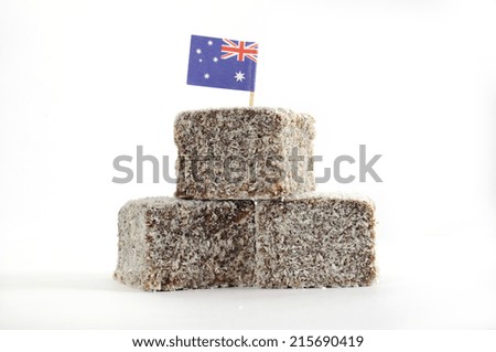 Stack of traditional Australian cake slice, Lamington squares, with chocolate icing and coconut with Australian flag on white background.