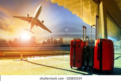 Gepäckstapel im Flughafen-Terminal und Passagierflugzeug, die in der Stadt über das Gebäude fliegen 