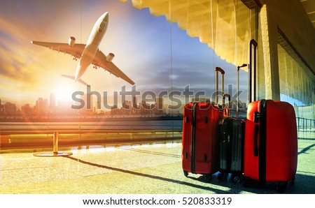 stack of traveling luggage in airport terminal and passenger plane flying over building in city 