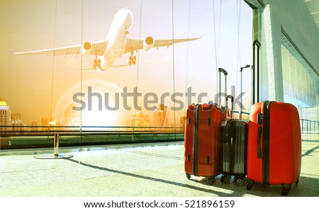 stack of traveling luggage in airport terminal building and passenger plane flying over urban scene 