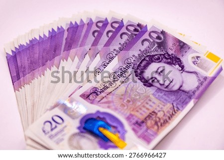 A stack of twenty pound banknotes from the Bank of England featuring Queen Elizabeth II, isolated on white background