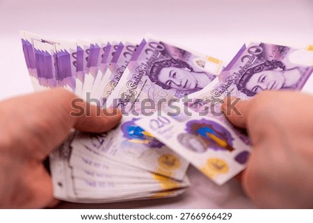 A stack of twenty pound banknotes from the Bank of England featuring Queen Elizabeth II in hands, isolated on white background