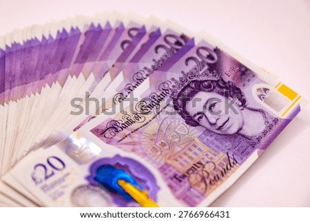A stack of twenty pound banknotes from the Bank of England featuring Queen Elizabeth II, isolated on white background