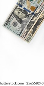 Stack of United States currency notes in denominations of 20 dollar bill, 50 dollar bill, 100 dollar bill, placed diagonally on a white background. Minimalistic composition suitable for financial, bus