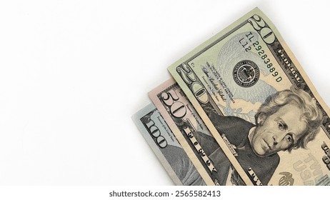 Stack of United States currency notes in denominations of 20 dollar bill, 50 dollar bill, 100 dollar bill, placed diagonally on a white background. Minimalistic composition suitable for financial, bus