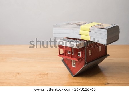 Stack US dollar banknotes on red house flipped over. Reverse mortgage loan concept. Reverse mortgage is home loans for seniors age sixty or older, the borrower do not have to pay any monthly repayment