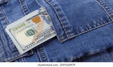 Stack of us dollars in the back pocket of blue jeans
