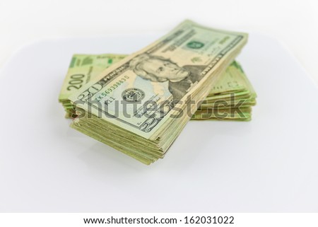 A stack of Us dollars bills and Mexian Pesos bills.