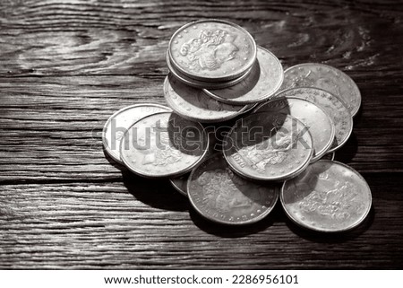 Stack of US old west dollar silver coins on wooden deck.