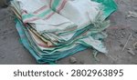 A stack of used empty plastic woven sacks or bags on the ground in rural farming area.