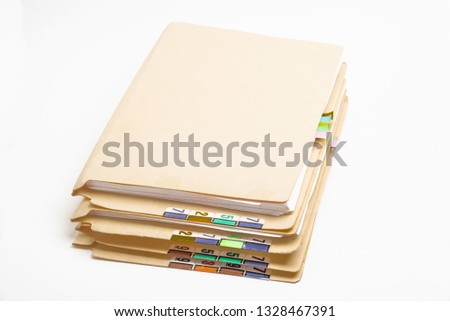 A stack of used folders in color-coded numbers and tabs containing paper documents.