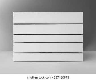 Stack Of Used White Books With Blank Spine On Gray Background