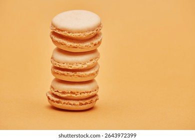 Stack of vanilla light beige color biscuits macaron cookies isolated on the bright solid fond plain bright sandy beige background