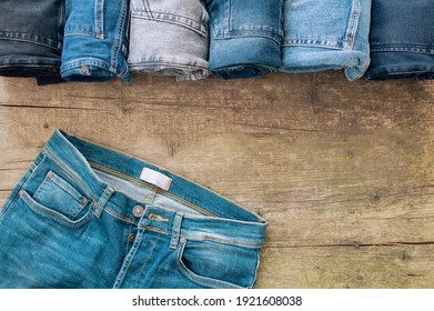 Stack of various denim jeans, trousers on wooden rustic background, fashion design 